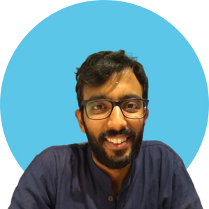 Headshot of Narayan Ramakrishnan who has dark hair a short beard and wears glasses with a dark blue collared shirt.
