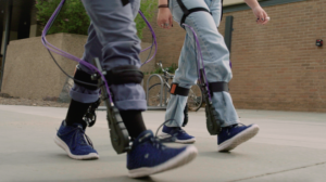 Two people walking with the Biomotum assistive device