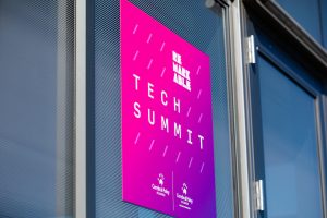 Window with a square pink poster that features the white text 'Remarkable Tech Summit' and includes the white CPA and CPARF logos in the bottom.